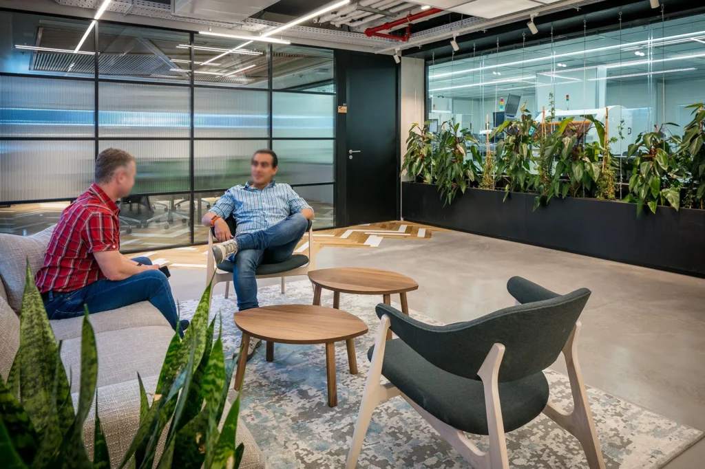 Employees seated in a planted lounge area at the Jabil Optics facility