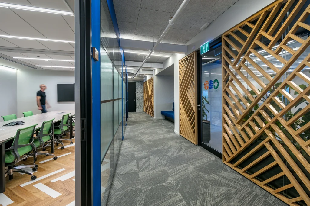 Office corridor with glazed meeting rooms and a timber screen at the Jabil Optics facility