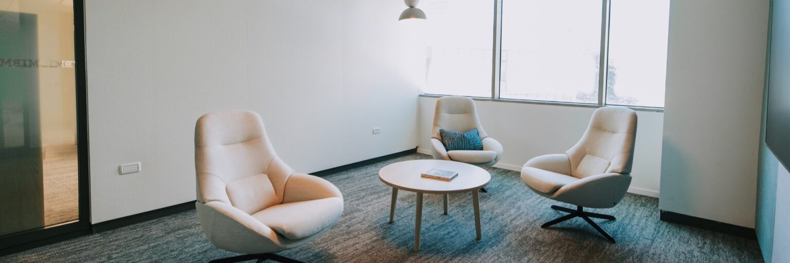 Waiting area with armchairs and a round table in a Domark office project