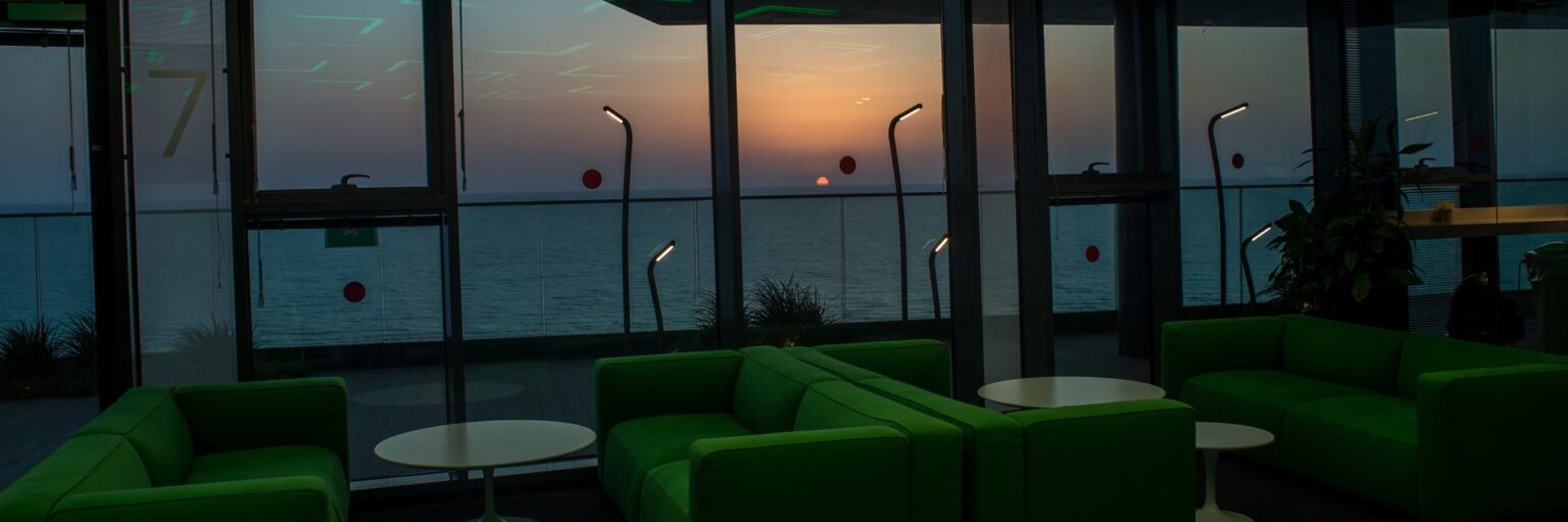Interior seating area beside full-height windows at dusk
