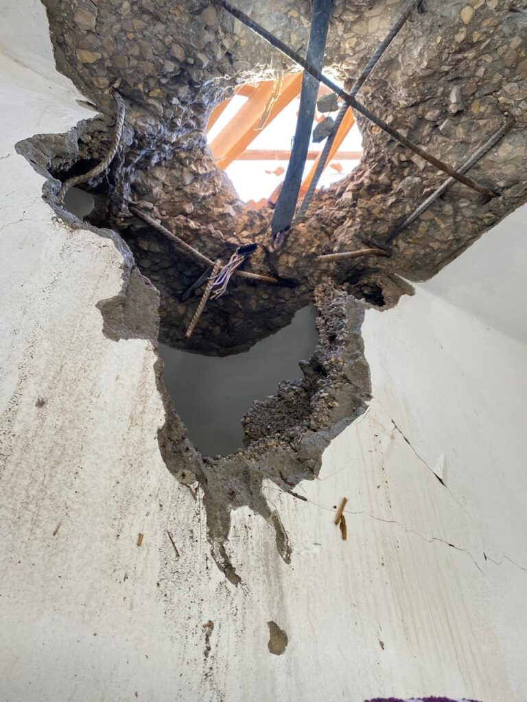 A concrete ceiling pierced by a strike